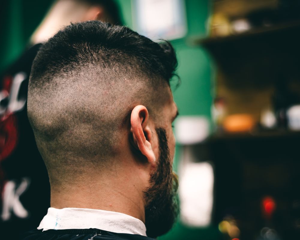 Nuca de un cliente con skin fade recién hecho y barba perfilada