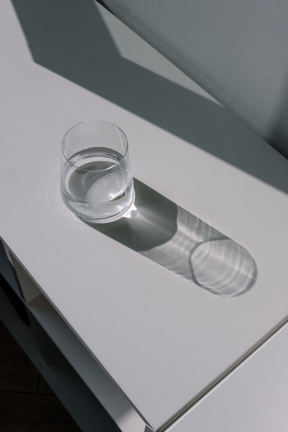 Vaso de agua sobre una mesa blanca con la luz del día